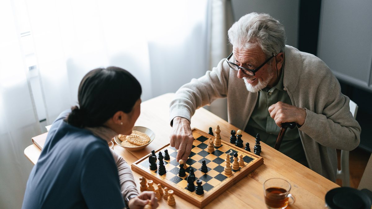 A caregiver playing chess with a senior client at home